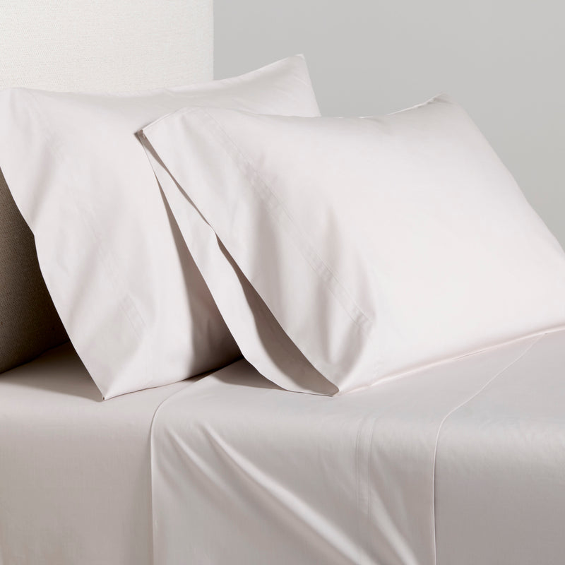 Grey Italian Percale Sheet Set with two pillowcases and flat sheet on a bed.