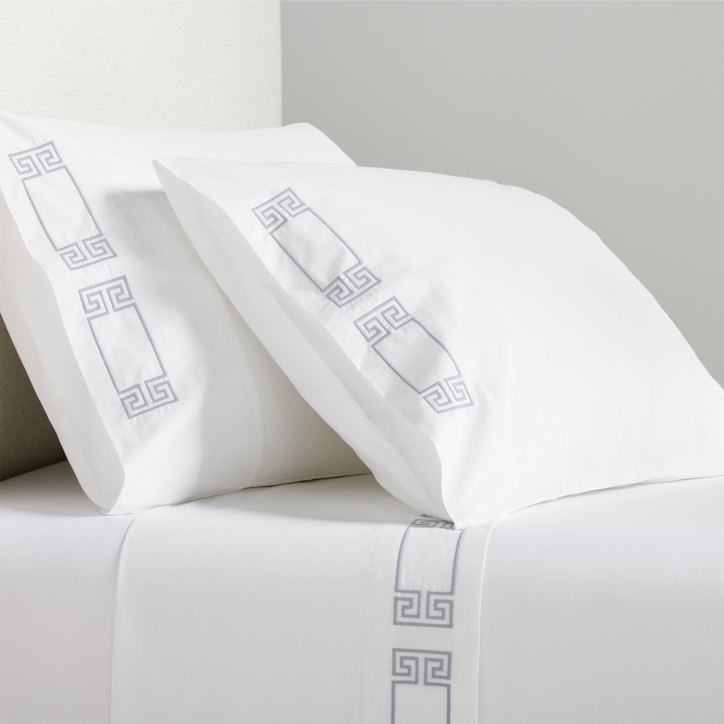 White percale sheet set with grey embroidered Greek key border on pillowcases and flat sheet.