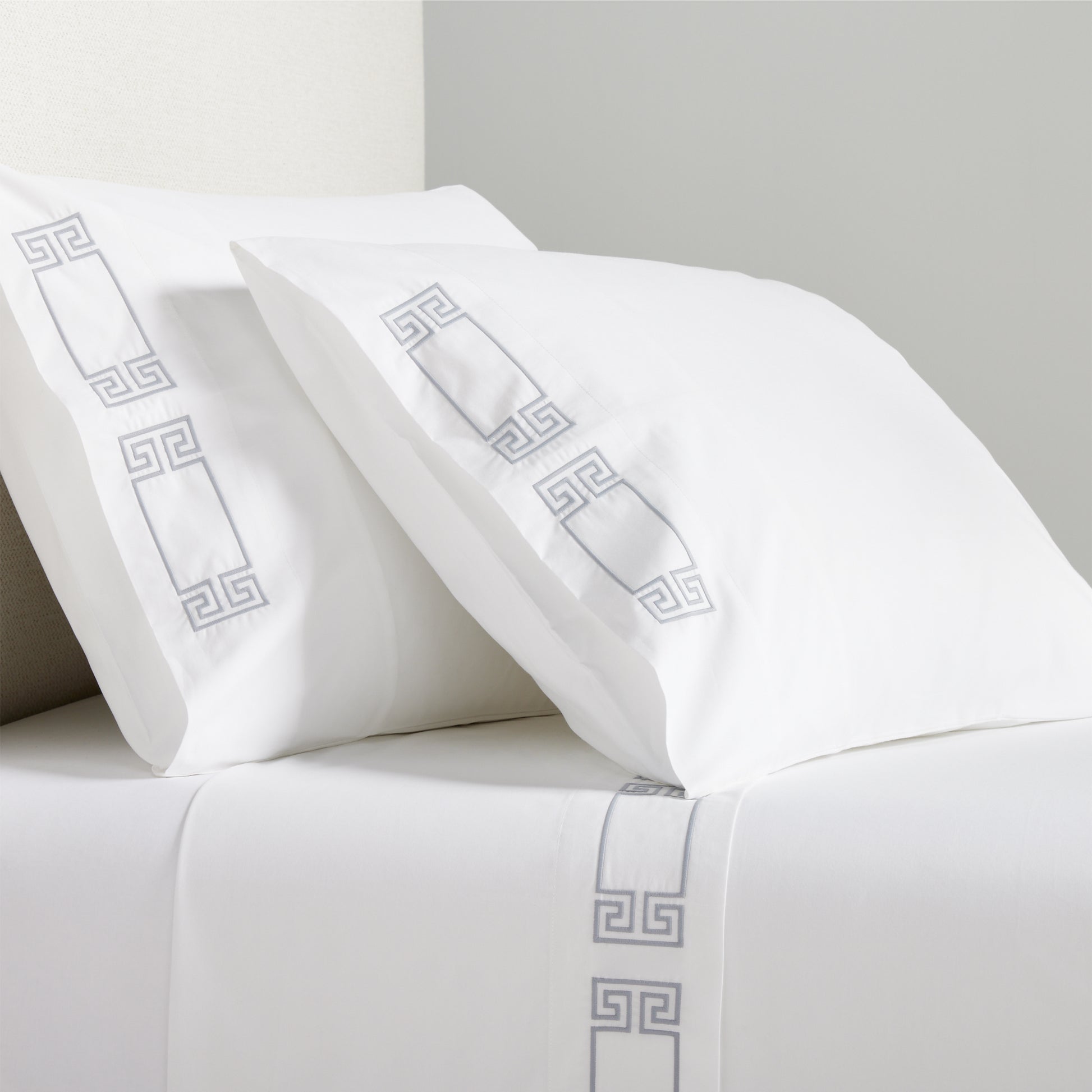 White percale sheet set with grey embroidered Greek key border on pillowcases and flat sheet.