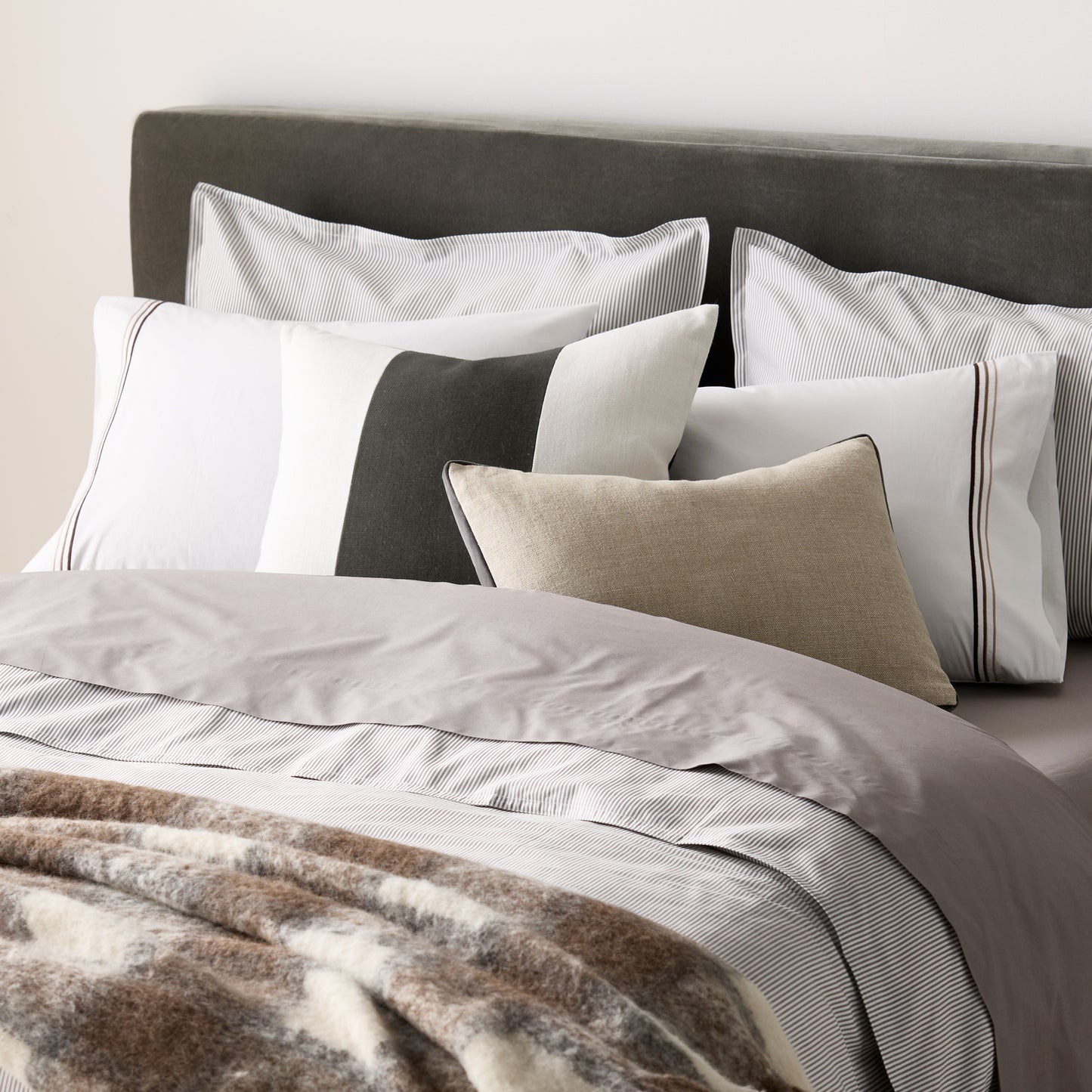 Grey stripe cotton-chambray pillow shams with 2" flange and double-needle stitching on a bed.
