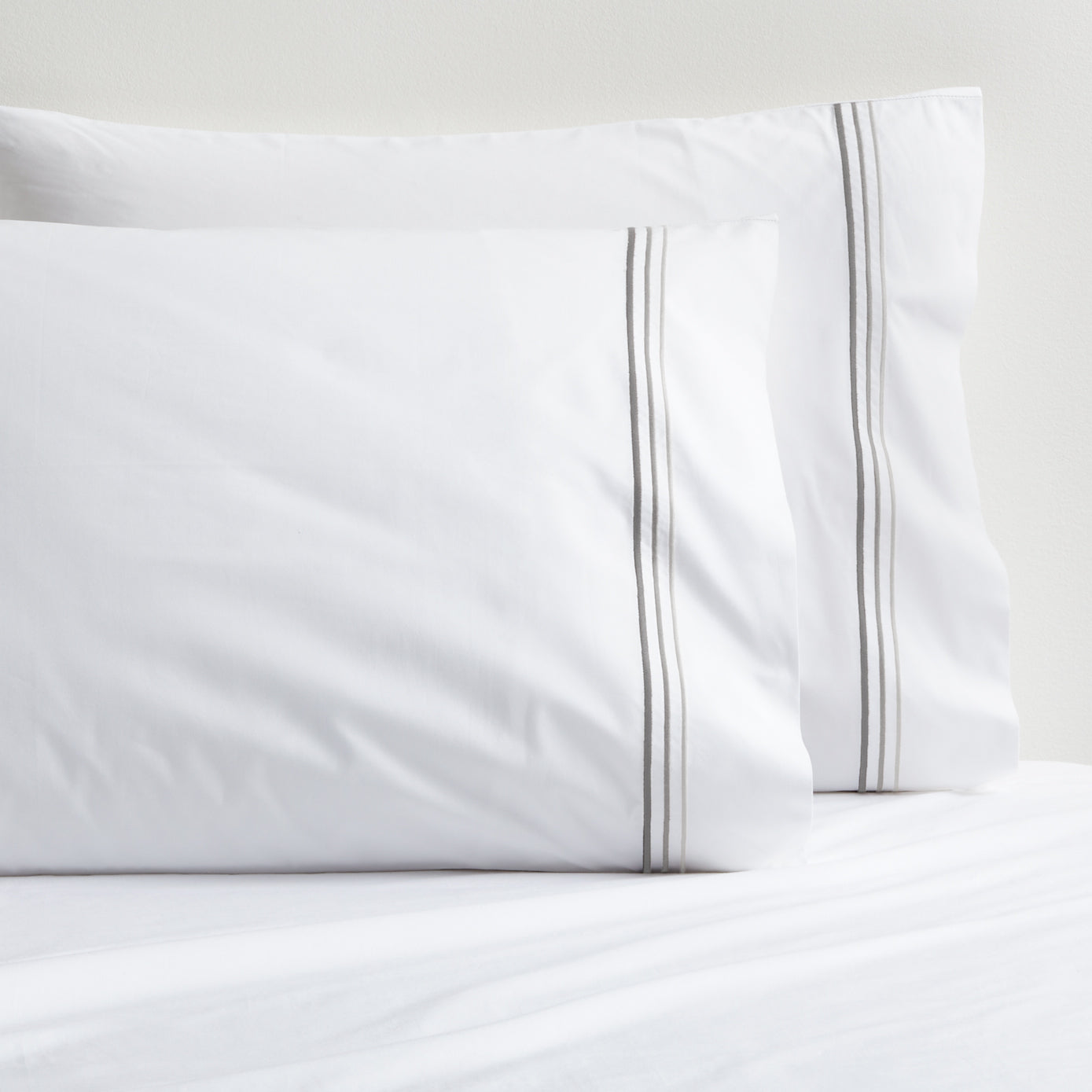 White percale pillowcases with three ombre grey embroidered stripes.