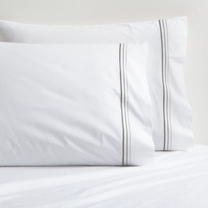 White percale pillowcases with three ombre grey embroidered stripes.