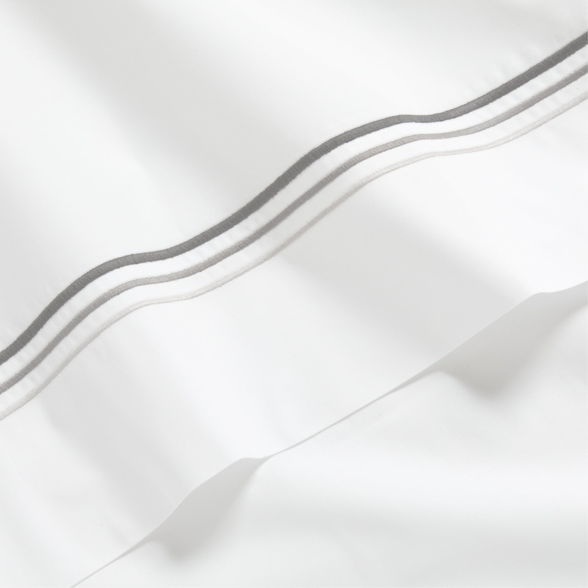 White percale sheet with three ombre grey embroidered triple stitches.