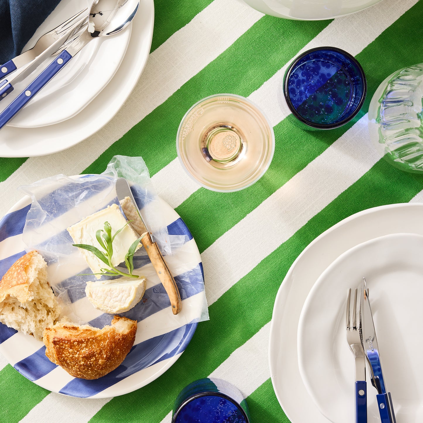 Handmade 12oz blue tortoise double old-fashioned glass on a green and white striped tablecloth.