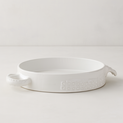 Handmade creamy white ceramic baker by Montes Doggett, 11"Dia, with organic shape and textured side detail.