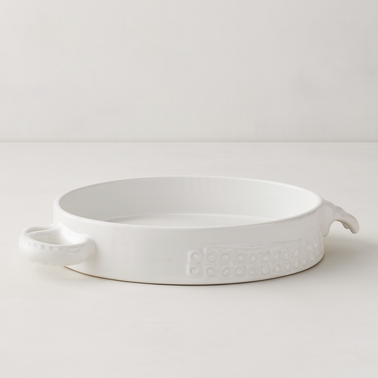 Handmade creamy white ceramic baker by Montes Doggett, 11"Dia, with organic shape and textured side detail.