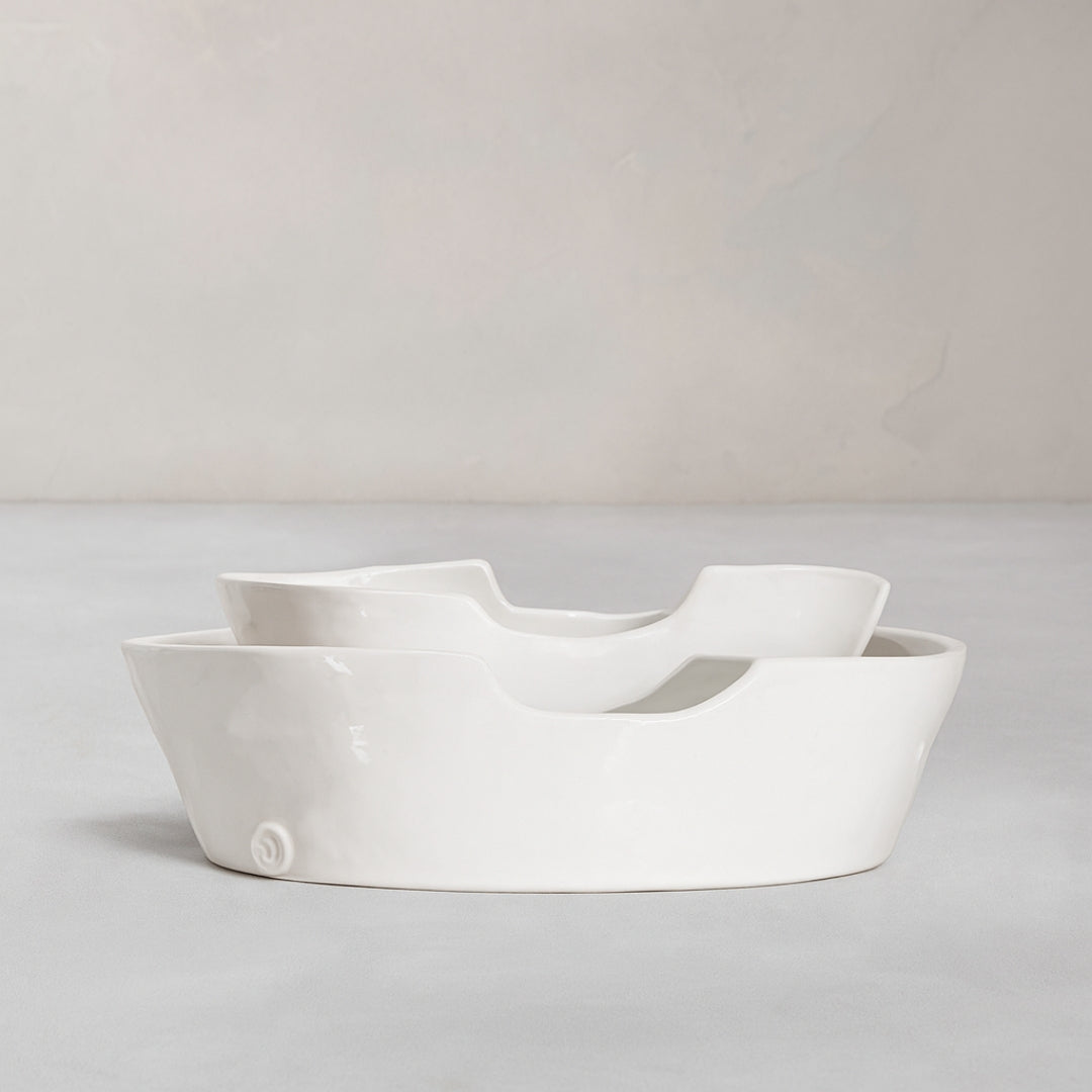Set of 2 handmade white ceramic Montes Doggett bowls with organic shapes, one nested inside the other.