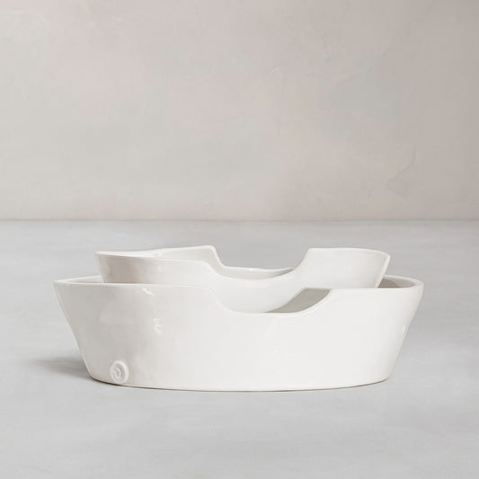 Set of 2 handmade white ceramic Montes Doggett bowls with organic shapes, one nested inside the other.