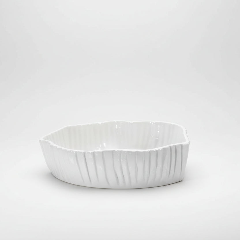 White, handmade Montes Doggett ceramic bowl with organic shape and textured vertical ridges.