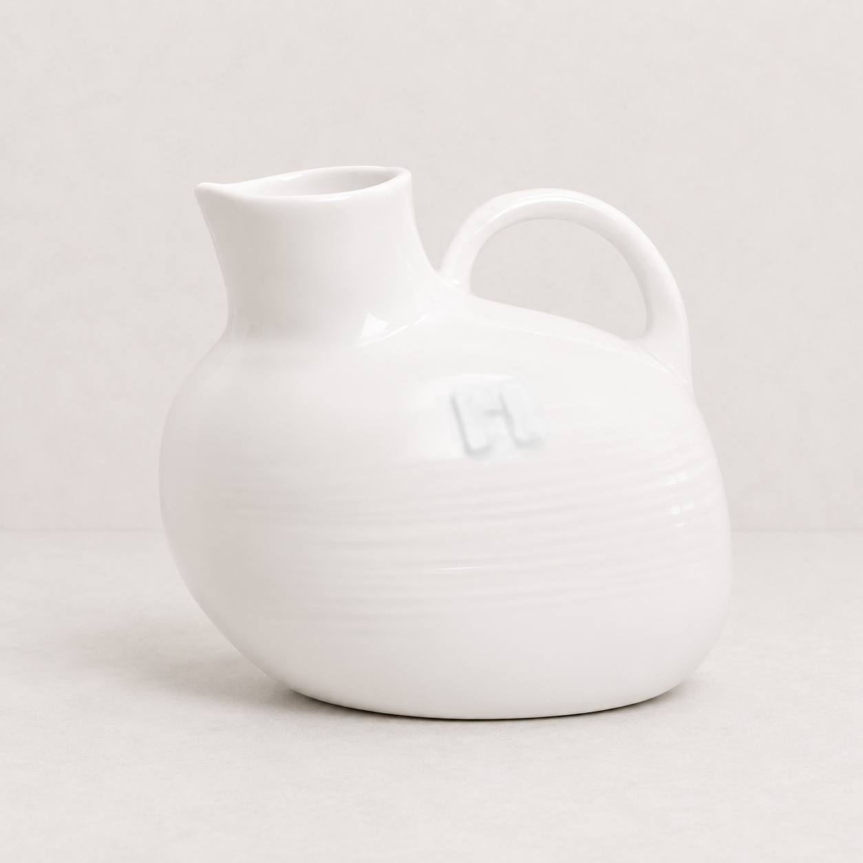 Handmade creamy white ceramic pitcher by Montes Doggett, 8"L x 6"W x 7"H, with handle and spout.