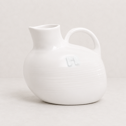 Handmade creamy white ceramic pitcher by Montes Doggett, 8"L x 6"W x 7"H, with handle and spout.