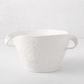 Handmade Montes Doggett ceramic serve bowl, creamy white glaze, sculptural wavy rim, and two small handles.