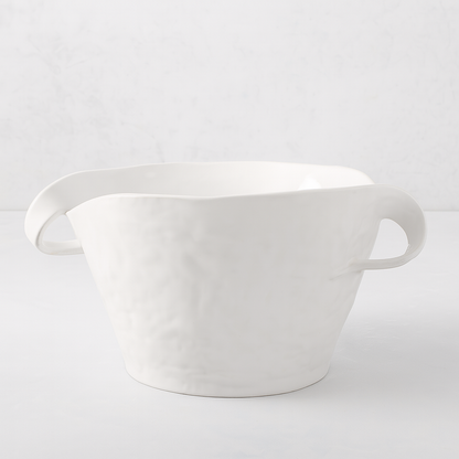 Handmade Montes Doggett ceramic serve bowl, creamy white glaze, sculptural wavy rim, and two small handles.