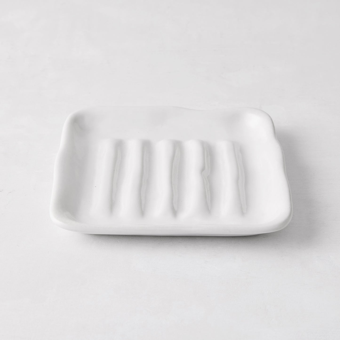 White handmade ceramic soap dish 5270 by Montes Doggett, 5" square, with organic shape and multiple ridges.
