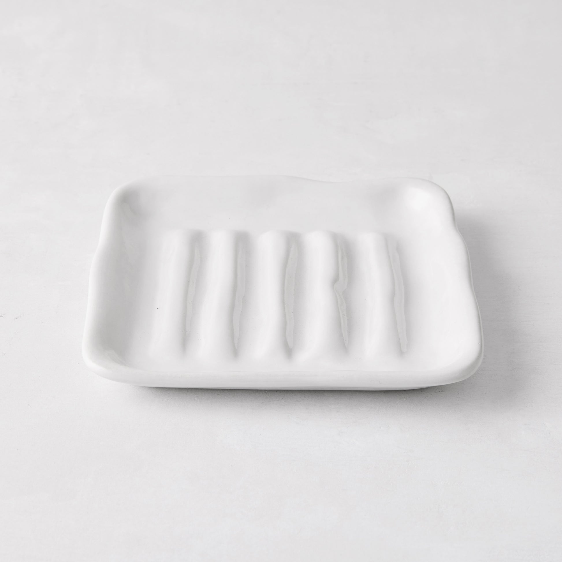 White handmade ceramic soap dish 5270 by Montes Doggett, 5" square, with organic shape and multiple ridges.