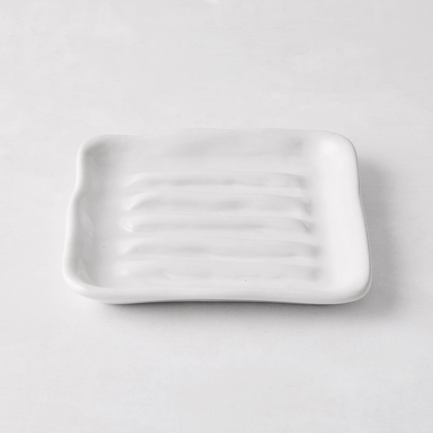 White handmade ceramic soap dish 5270 by Montes Doggett, 5" square with organic shape and multiple ridges.