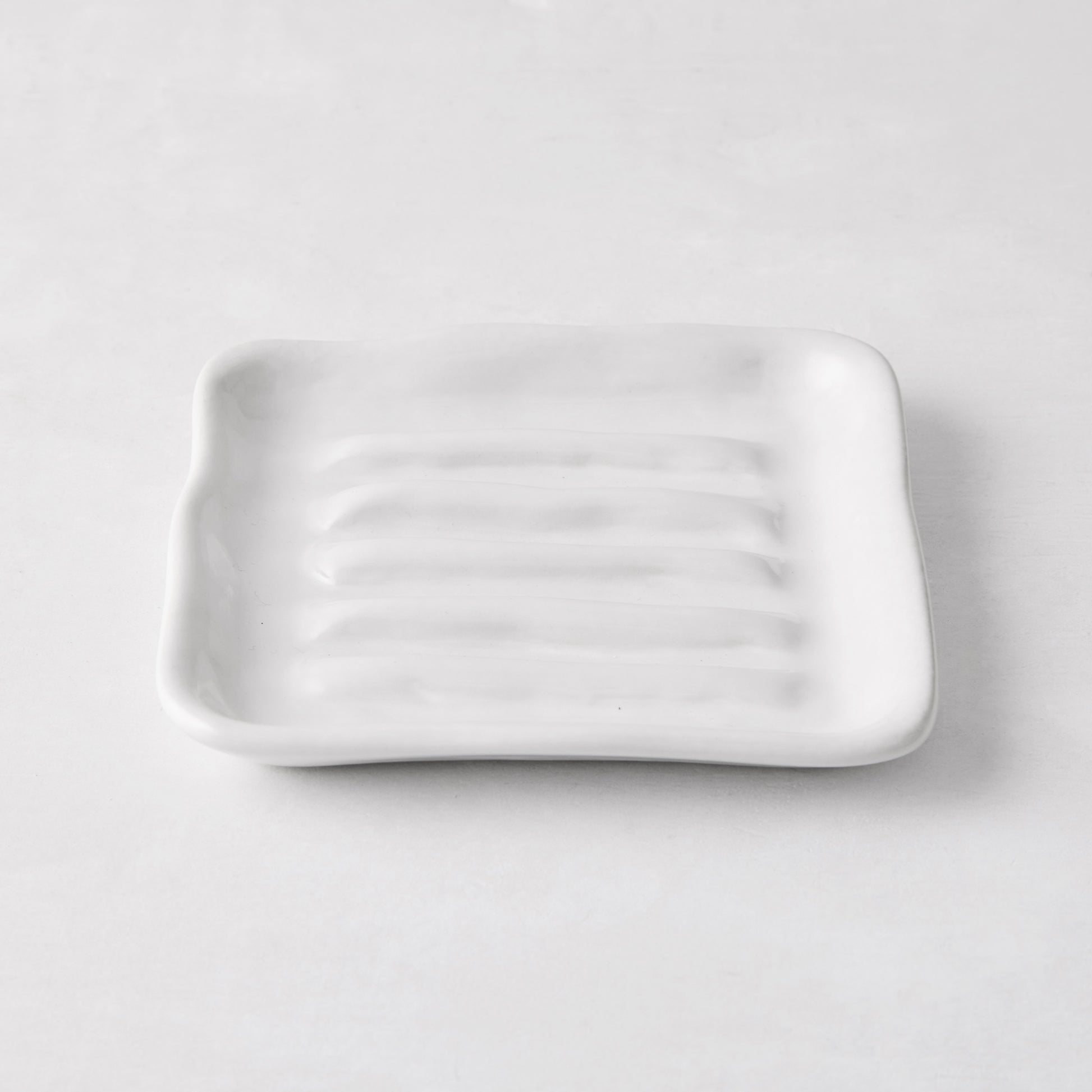 White handmade ceramic soap dish 5270 by Montes Doggett, 5" square with organic shape and multiple ridges.