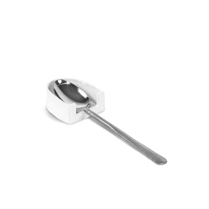 Handmade creamy white ceramic spoon rest by Montes Doggett, holding a silver spoon.