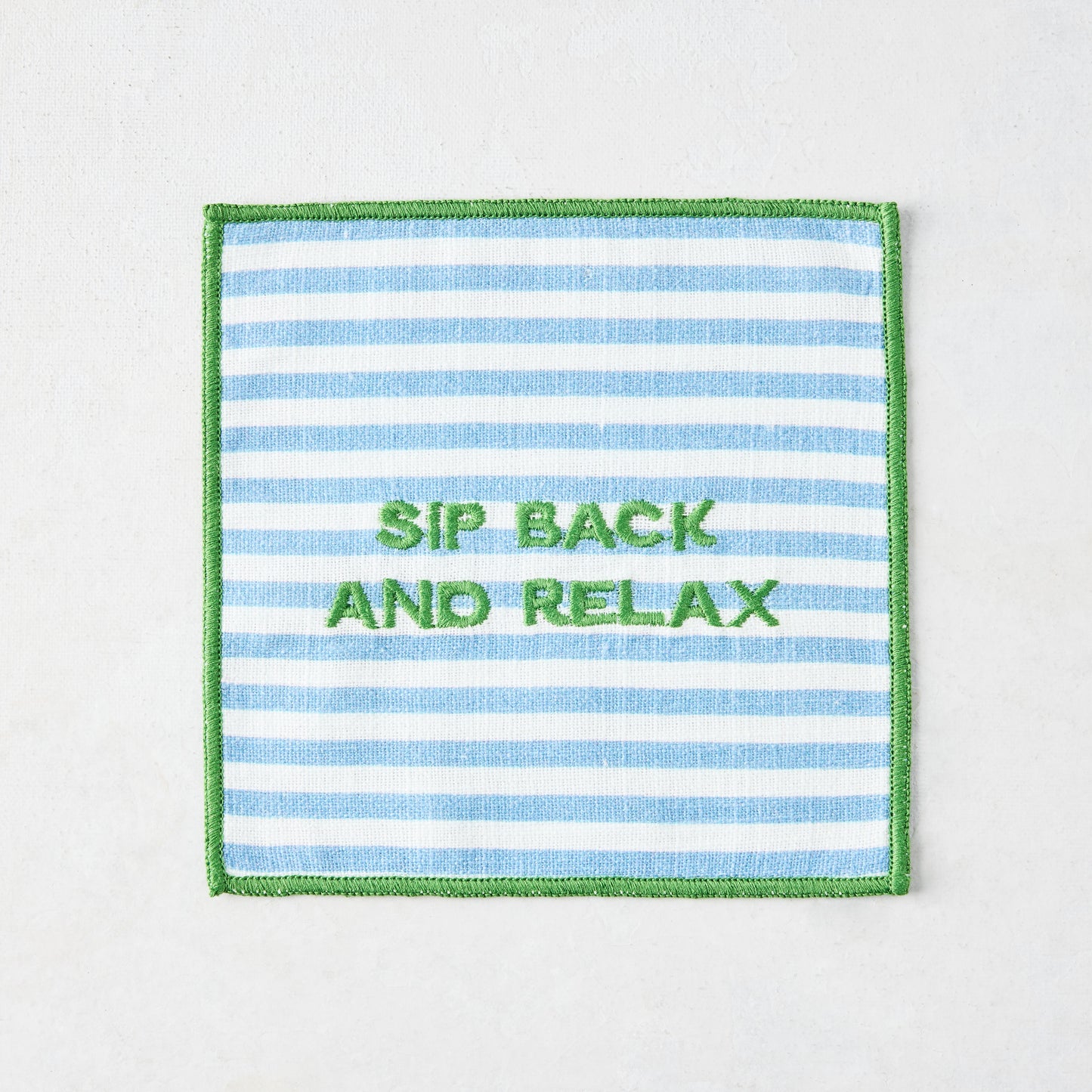 Blue and white striped cotton coaster with green embroidered "SIP BACK AND RELAX" text and green border.