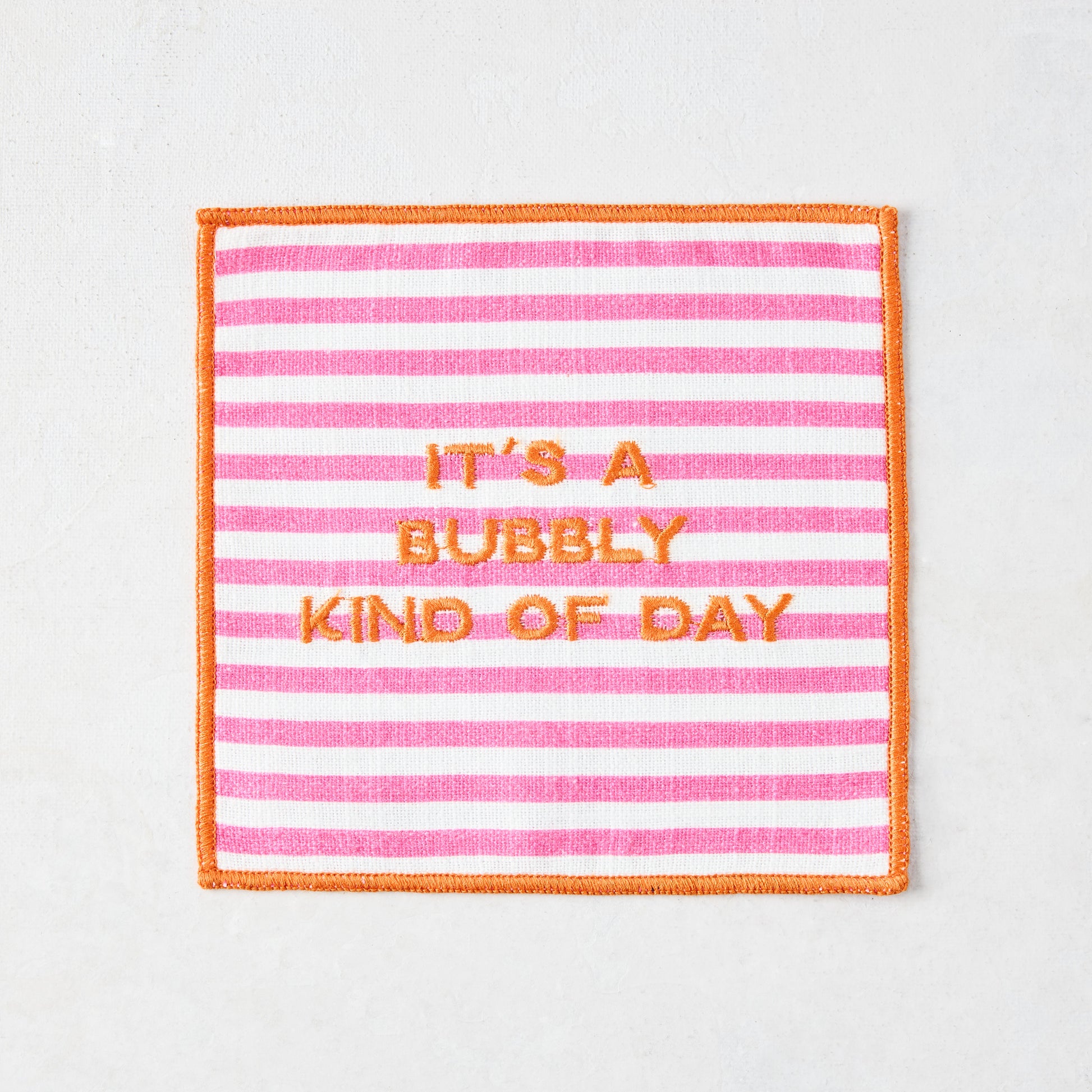 Square cotton coaster with pink and white stripes, orange embroidered border, and "IT'S A BUBBLY KIND OF DAY" text.