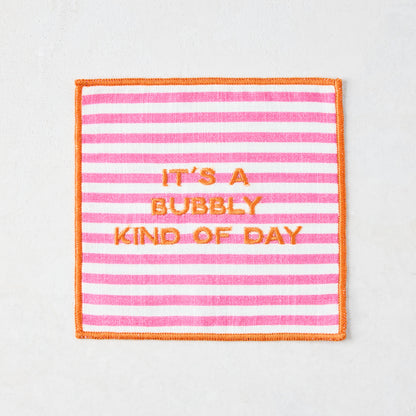 Square cotton coaster with pink and white stripes, orange embroidered border, and "IT'S A BUBBLY KIND OF DAY" text.