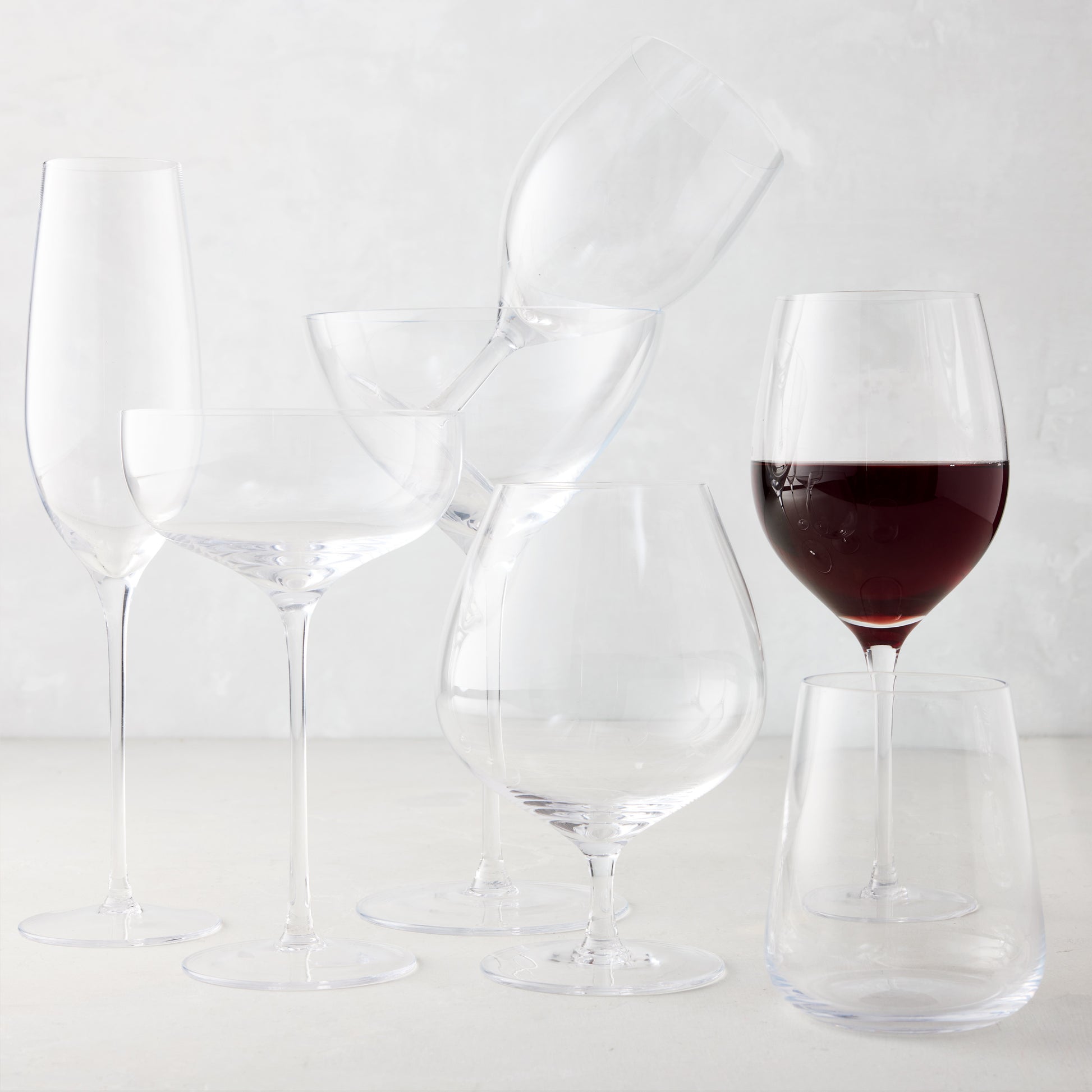Clear mouth-blown HG Heritage Cognac Glass with a generous bowl, alongside other clear drinkware.