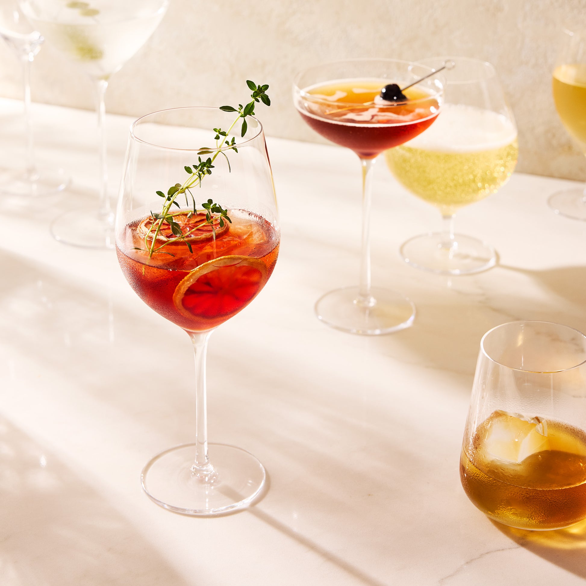 Clear, mouth-blown HG Heritage Wine Glass filled with a red cocktail, garnished with orange slices and thyme.