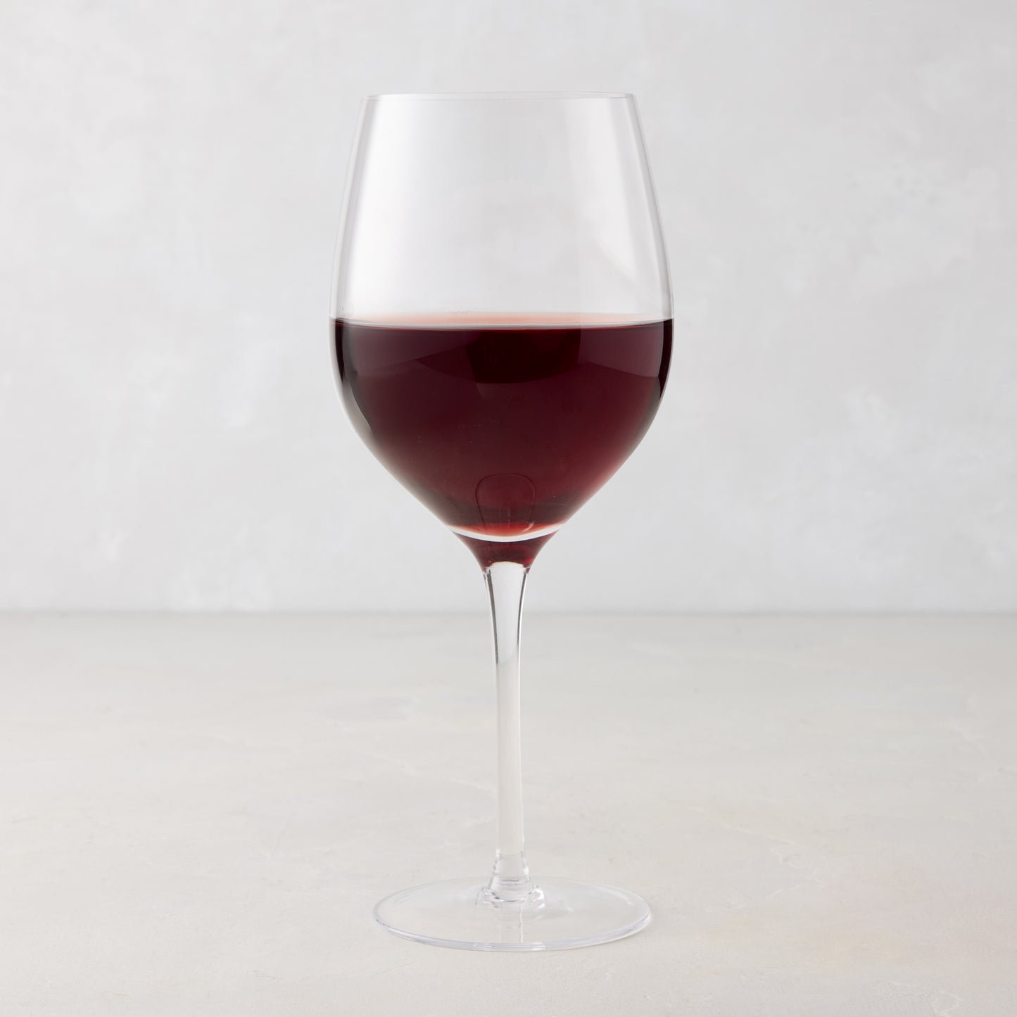 HG Heritage Wine Glass, clear mouth-blown glass, filled with red wine, on a light background.