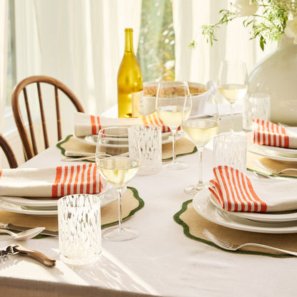HG Heritage Wine Glass on a set table with white wine, striped napkins, and green placemats.
