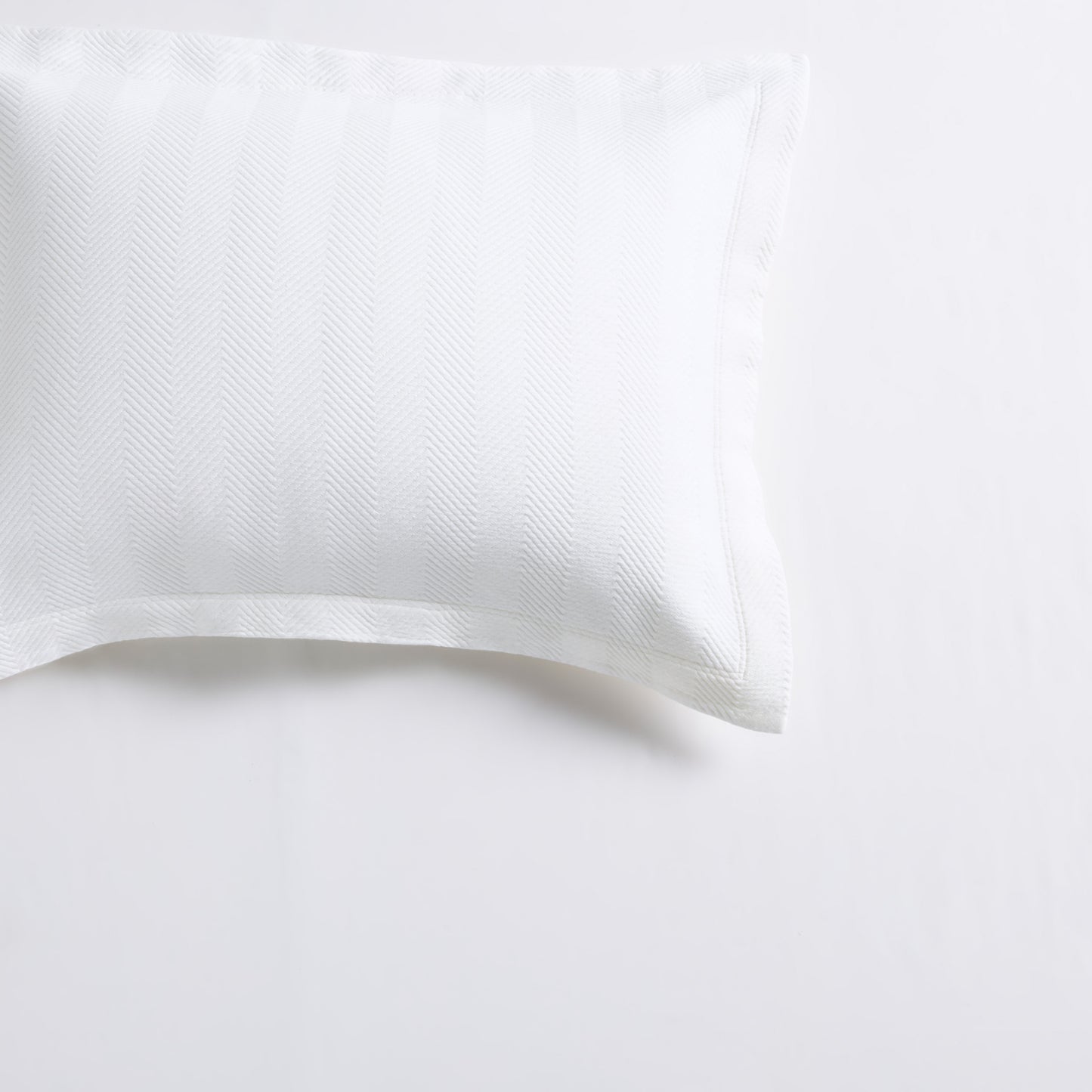 White cotton matelassé pillow sham with a subtle herringbone pattern and 2-inch hem.