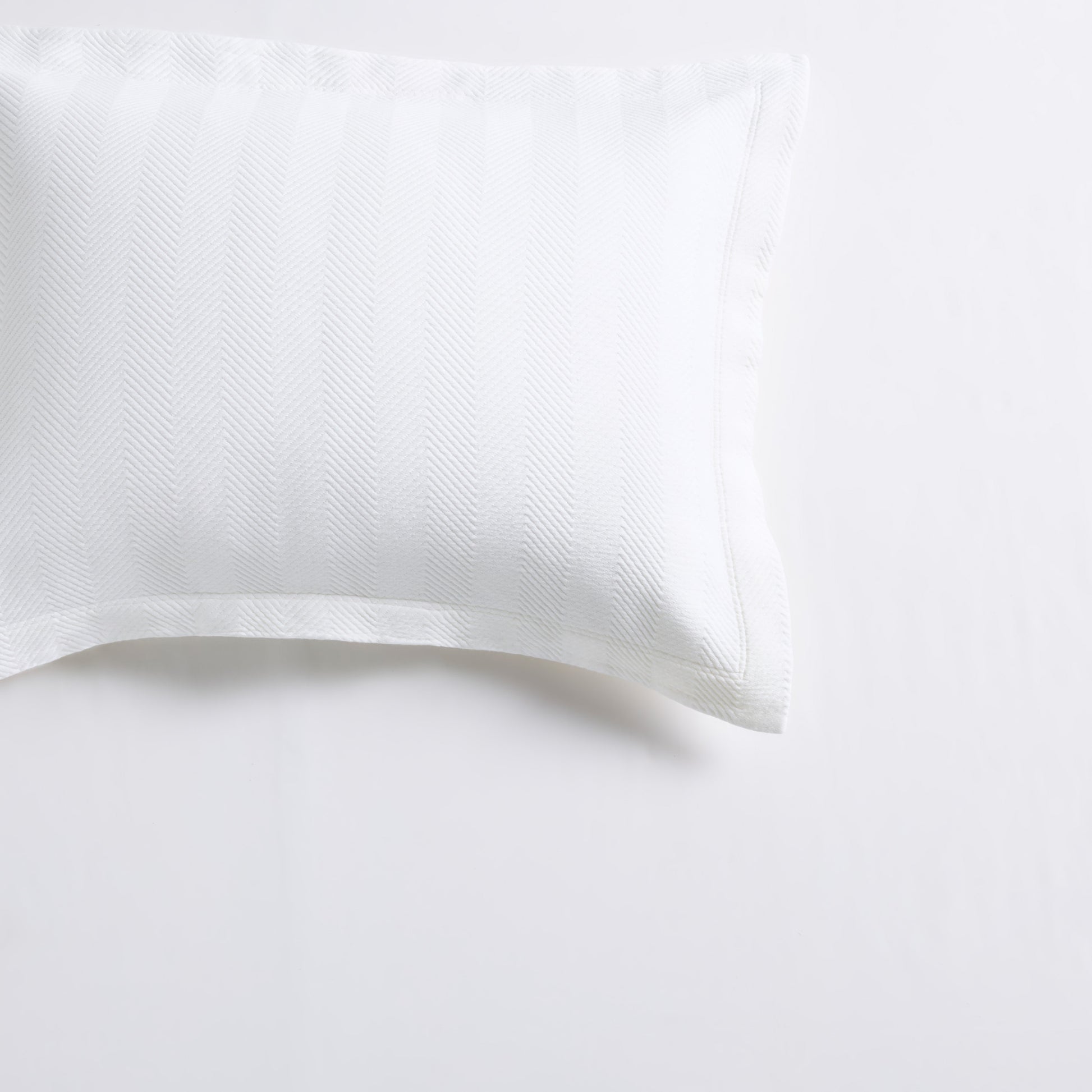 White cotton matelassé pillow sham with a subtle herringbone pattern and 2-inch hem.