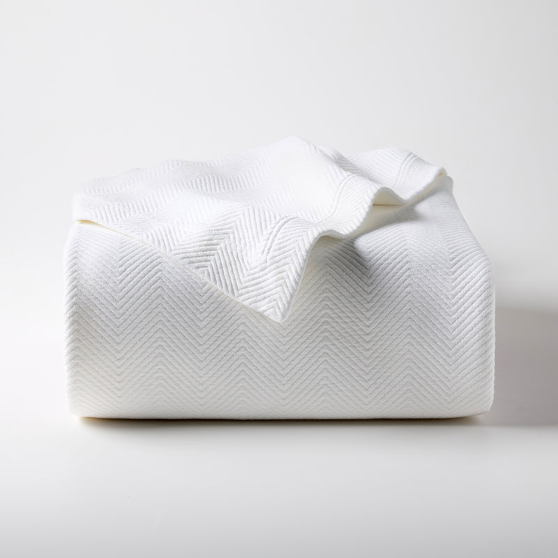 White Queen Matelassé Coverlet, 100% cotton with a subtle herringbone pattern, folded on a white surface.