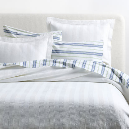 White Herringbone Matelassé Pillow Shams, 100% cotton, with subtle texture and a striped accent pillow.