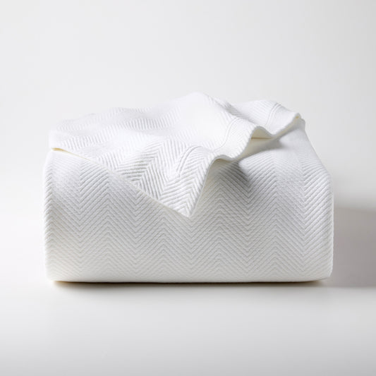 White Queen Matelassé Coverlet, 100% cotton with a subtle herringbone pattern, folded on a white surface.