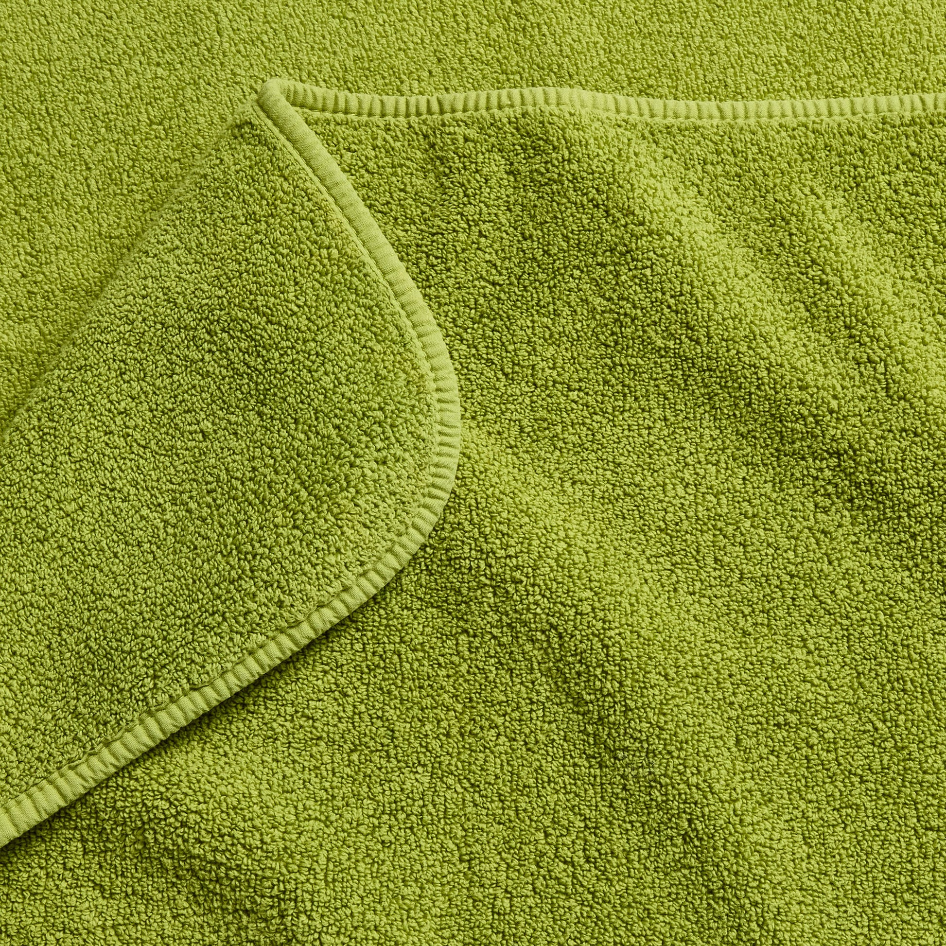 Aloe green zero-twist cotton bath towel with matching bias piping detail.