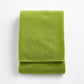 Folded aloe green Signature bath towel made of soft zero-twist cotton with bias piping detail.