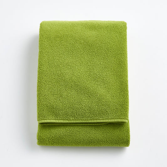 Folded aloe green Signature bath towel made of soft zero-twist cotton with bias piping detail.