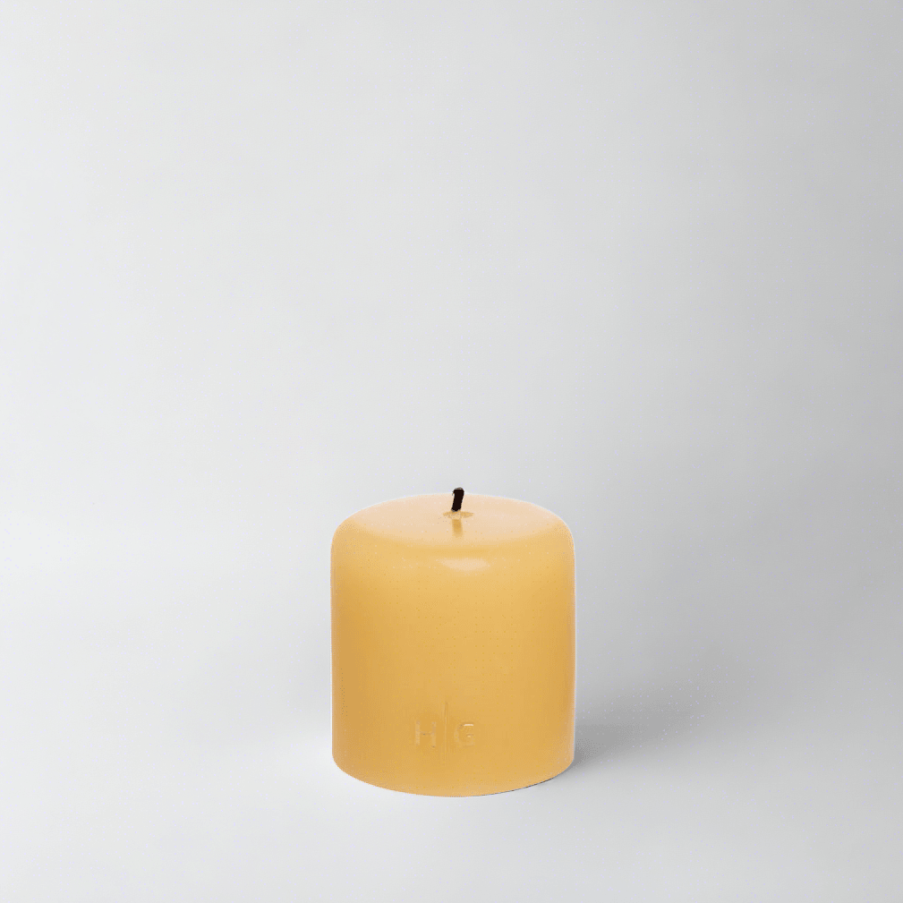 HG Amber Unscented Pillar Candle, 3"x3", with a gold embossed HG logo and black wick.