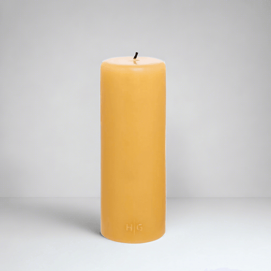 HG Amber Unscented Pillar Candle, 3"x8", with a gold embossed HG logo and black wick.