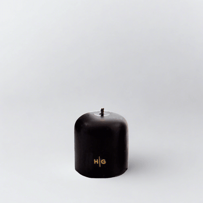 HG Black 3"x3" unscented pillar candle with gold embossed HG logo and oversized cotton wick.