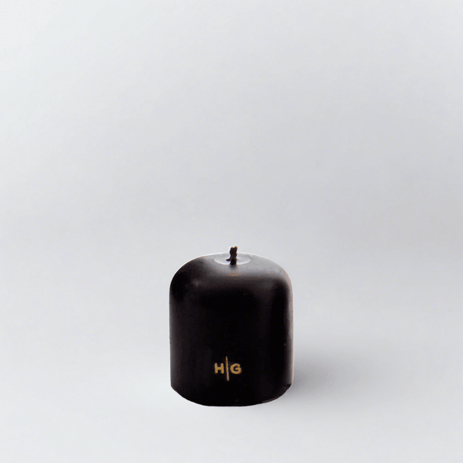 HG Black 3"x3" unscented pillar candle with gold embossed HG logo and oversized cotton wick.