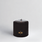 HG Black Unscented Pillar Candle, 4"x4", with gold embossed HG logo and oversized cotton wick.