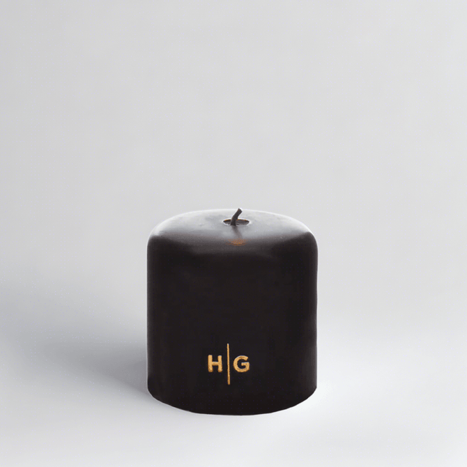 HG Black Unscented Pillar Candle, 4"x4", with gold embossed HG logo and oversized cotton wick.