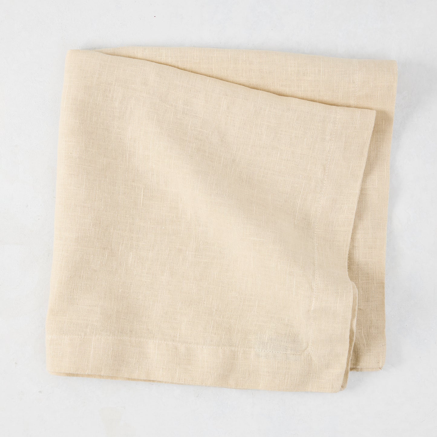 HG Buttermilk Hand-Dyed Linen Napkin, 22", folded, light beige with subtle texture.