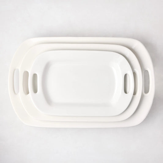 Set of 3 white ceramic serving platters with handles, nested from small to large.