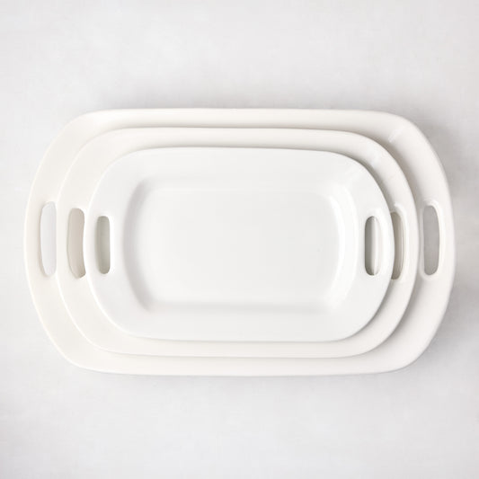 Set of 3 white ceramic serving platters with handles, nested from small to large.