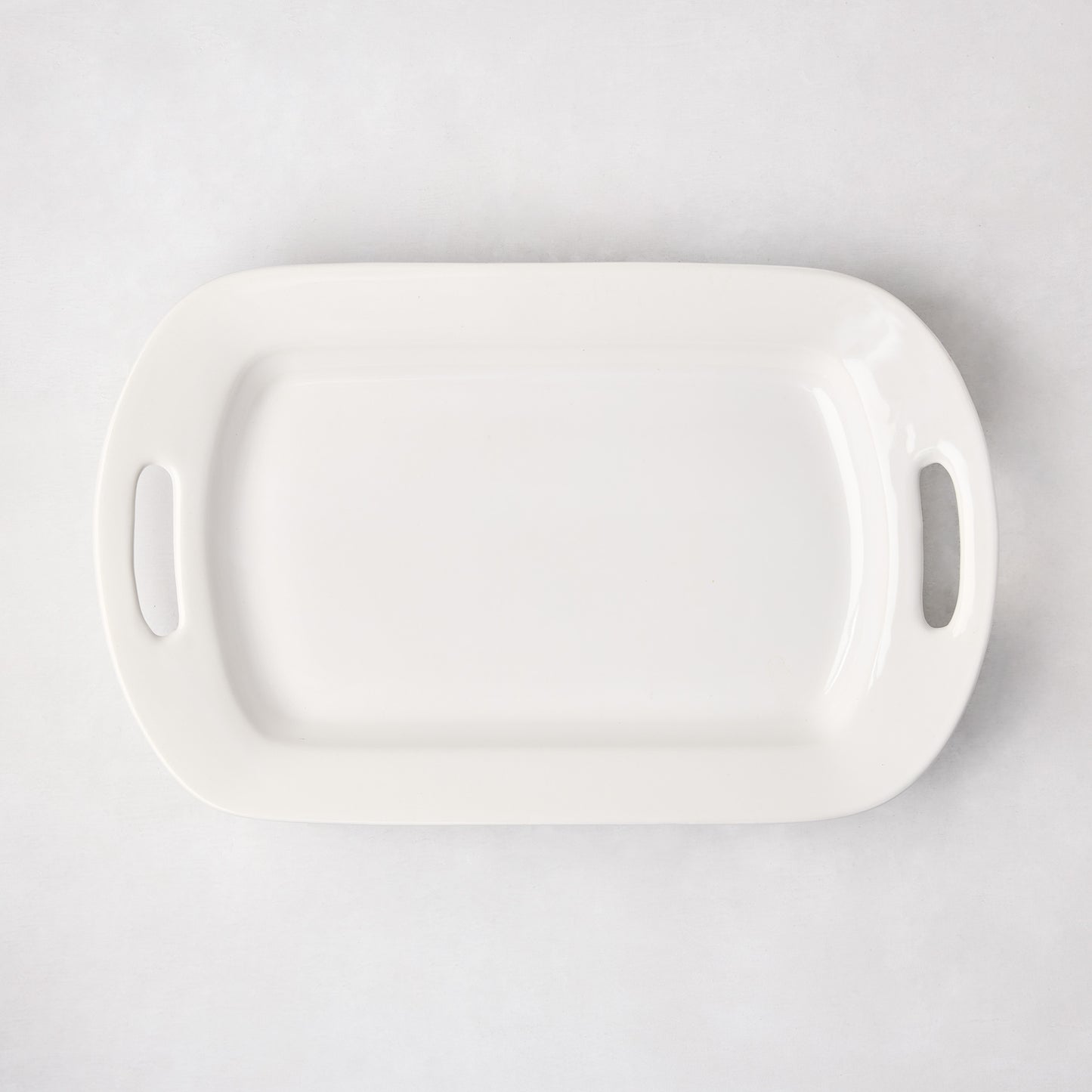 White ceramic serving platter with handles, 11"W x 18"L, from HG Ceramic Medium collection.