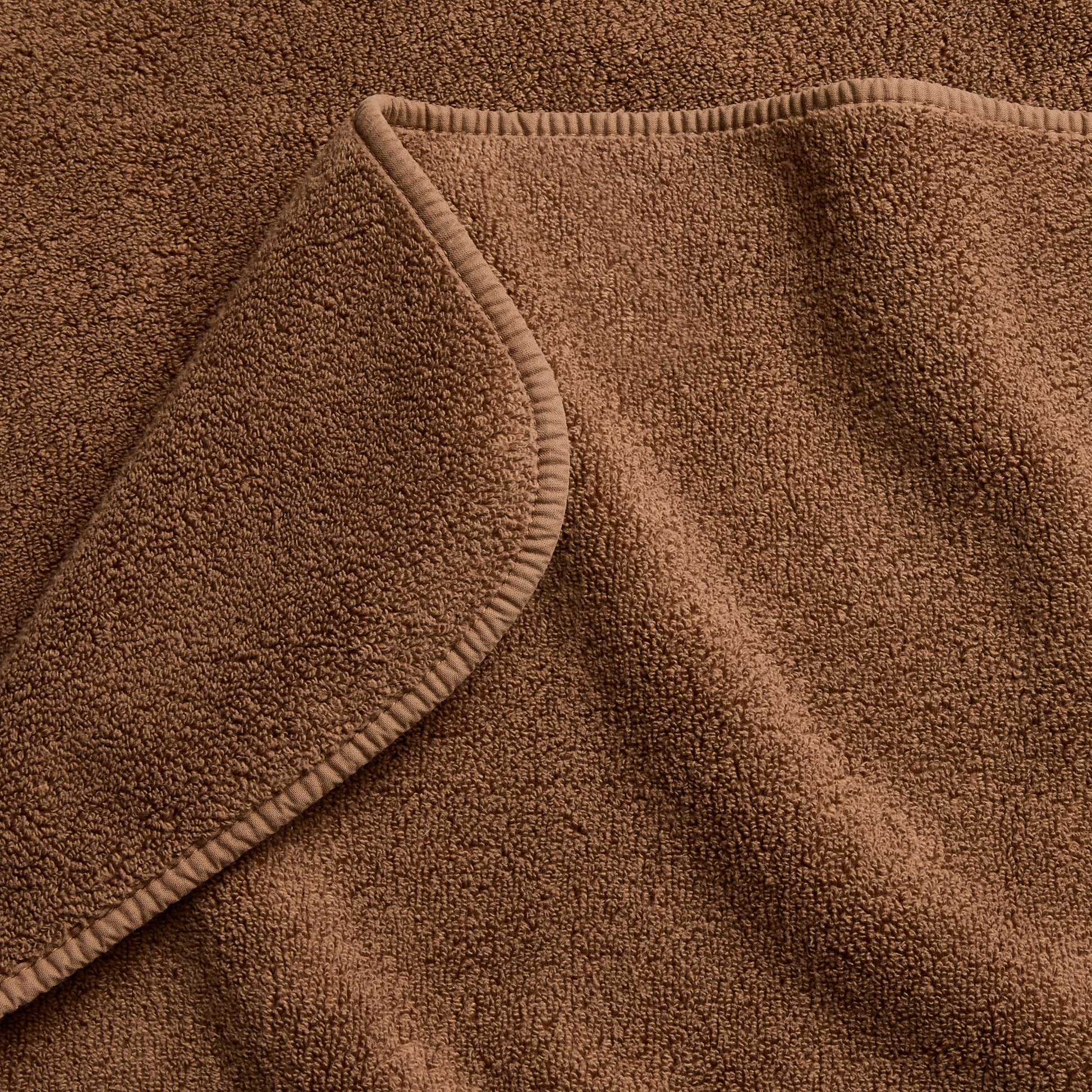 Coffee brown signature bath towel with a soft, plush cotton terry texture and a finished hemmed edge.