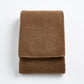 Folded coffee brown Signature bath towel made of soft, plush cotton terry fabric on a white background.