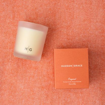 HG Original Scented Candle in frosted glass with orange box on a Mandarin Orange Italian Herringbone Throw.